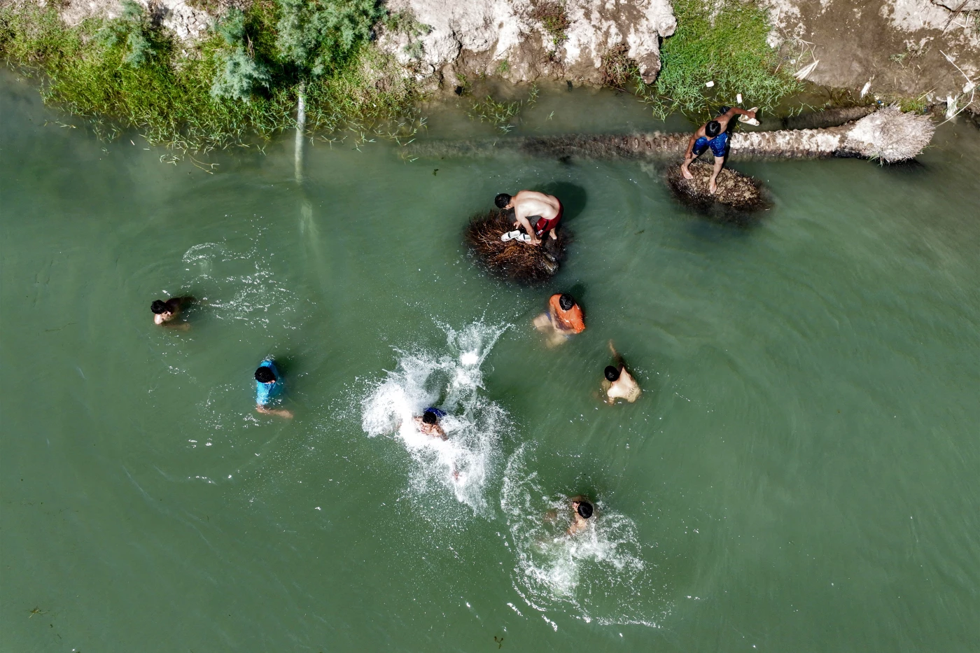 Image of Iraqis flock to river or ice rink to escape searing heat